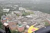 Luftblick auf einen großen Industriekomplex mit Gebäuden, Straßen und Wald im Hintergrund.