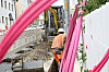 Telekom-Baustelle mit Glasfaserarbeiten, orange gekleideter Arbeiter und pinken Kabelschläuchen entlang eines Grabens.