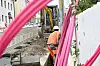 Telekom-Baustelle mit Glasfaserarbeiten, orange gekleideter Arbeiter und pinken Kabelschläuchen entlang eines Grabens.