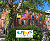 Buntes Schild „Hofinale – Wir machen Kunst!“ vor rotem Backsteingebäude und Bäumen.