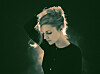 Agnes Obel steht im Gegenlicht auf der Bühne und blickt nach unten.