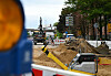 Baustelle in der Buxtehuder Straße nach Rohrbruch mit Absperrungen, Erdreich und Bagger.