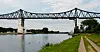 Eisenbahn-Hochbrücke Rendsburg über dem Nord-Ostsee-Kanal, Uferweg im Grünen am Wasser.
