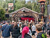 Menschenmenge vor überdachter Open-Air-Bühne im Park mit rotem Bühnenhintergrund.