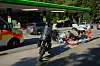 Rettungskräfte sichern an einer Tankstelle eine Unfallstelle mit Motorrad und Trümmern auf der Fahrbahn.