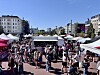 Menschen bewegen sich zwischen weißen und pinken Ständen auf einem belebten Straßenfest in der Innenstadt.