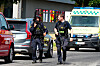Polizeibeamte sichern einen Tatort, im Hintergrund steht ein Rettungswagen.