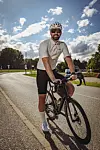 Rennradfahrer mit Helm steht auf einer Straße am Elbdeich neben seinem Fahrrad.