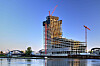 Elbtower im Bau mit Kränen an der Hamburger Hafencity, davor Wasser, Brücken und Uferbebauung.