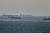Mehrere Tanker und Frachtschiffe verkehren im Golf von Oman vor einer dunstigen Horizontlinie.