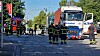 Feuerwehrleute sichern eine Straße neben einem Einsatzfahrzeug und weiteren Rettungsfahrzeugen.