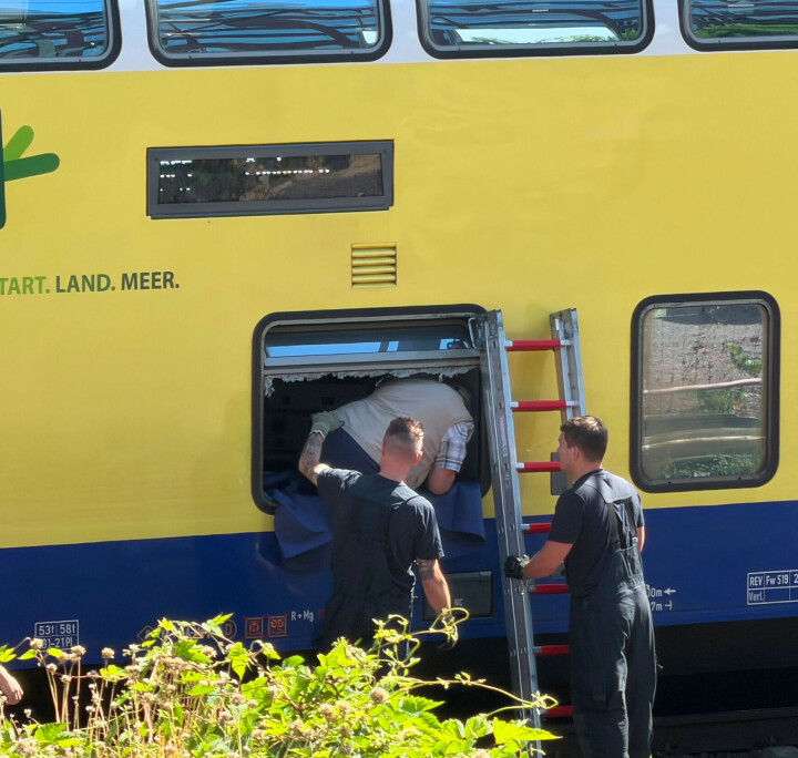 Fahrgäste steigen an der geöffneten Tür in einen gelben Regionalzug ein.