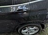Seitliche Ansicht eines dunklen Autos mit Türgriff, Reflexionen und sichtbarem Hinterrad.
