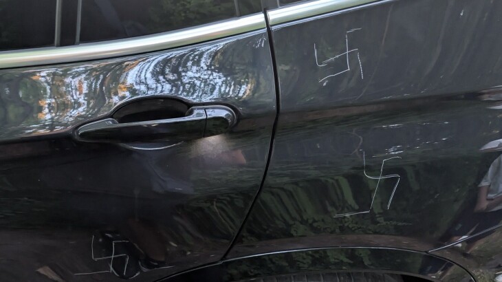 Seitliche Ansicht eines dunklen Autos mit Türgriff, Reflexionen und sichtbarem Hinterrad.