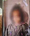 Unkenntlich gemachte Person in grauer Jacke hinter einer reflektierenden Glasscheibe