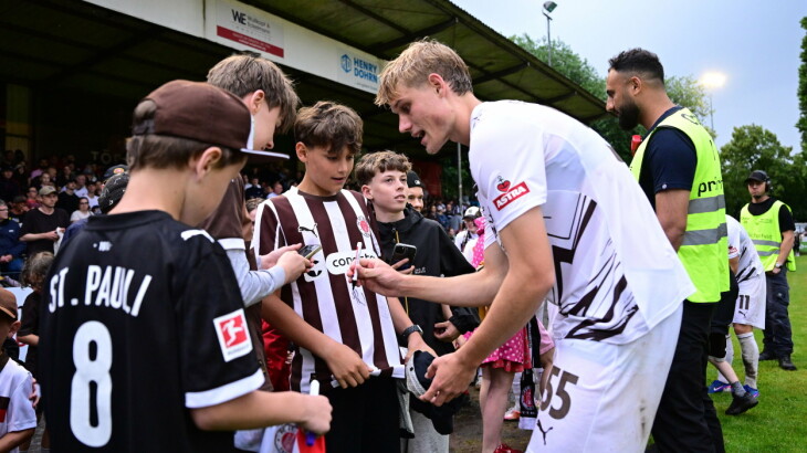 Sam Klein vom FC St. Pauli unterschreibt bei einem Testspiel in Hamburg für Fans.