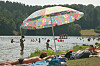 Badegäste schwimmen und sonnen sich am Twistesee bei Wetterburg unter einem bunten Sonnenschirm.