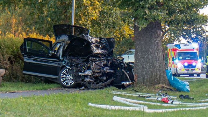 Mehrere Einsatzfahrzeuge stehen an einer Landstraße, ein Feuerwehrfahrzeug rechts, dunkler Gegenstand im Gras vorn.