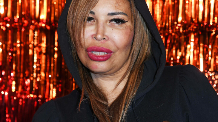 Patricia Blanco posiert im Moschino-Hoodie vor einer rot-goldenen Glitzerwand in Berlin.