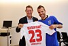 Frank Arnesen und Rafael van der Vaart zeigen ein weißes HSV-Trikot mit der Nummer 23 in einem Innenraum.