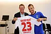 Frank Arnesen und Rafael van der Vaart zeigen ein weißes HSV-Trikot mit der Nummer 23 in einem Innenraum.