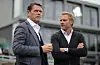 Frank Arnesen und Thorsten Fink stehen vor einem modernen Gebäude; einer spricht, der andere verschränkt die Arme.