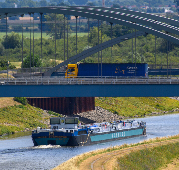 Frachtkahn fährt unter einer Autobahnbrücke durch einen Kanal der Schleuse Rothensee.