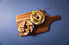 Zwei belegte Bagels mit Gewürzmischung und Chiliflocken auf einem Holzbrett