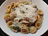 Orecchiette mit Kräutern und geriebenem Käse auf einem weißen Teller