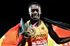 Owen Ansah zeigt eine Medaille und hält eine deutsche Fahne vor dunklem Hintergrund.