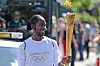 Jason Arday trägt die olympische Fackel bei der London-2012-Fackellaufstrecke durch eine belebte Straße.
