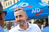Ulrich Siegmund spricht an einem AfD-Infostand mit Bürgern; hinter ihm ist ein blaues AfD-Zelt zu sehen.