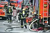 Feuerwehrleute löschen einen Dachstuhlbrand am Eppendorfer Baum; Schläuche und Einsatzfahrzeuge stehen auf der Straße.
