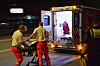 Zwei Einsatzkräfte schieben nachts eine Trage zu einem geöffneten Rettungsfahrzeug.