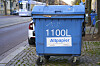 Blaue 1100-Liter-Altpapiertonne am Straßenbahnverkehr auf einem Gehweg in Magdeburg