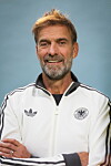 Jürgen Klopp posiert in Frankfurt im weißen DFB-Trainingsanzug vor blauem Hintergrund.