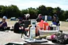 Menschen sitzen bei einem Picknick im Grünen an einem Tisch mit Getränken und Lebensmitteln.