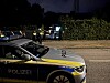 Streifenwagen der Polizei im Vordergrund, dahinter Einsatzkräfte an einer nächtlichen Straße.