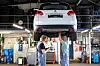 Zwei Mechaniker arbeiten unter einem angehobenen Mitsubishi-SUV in einer Kfz-Werkstatt.