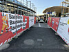 Abgesperrter Fußweg führt zwischen roten Baustellenzäunen durch eine innerstädtische Baustelle.