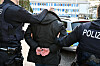 Zwei Polizisten führen eine gefesselte Person in Kiel ab.