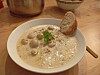 Schale cremige Pilzsuppe mit Kräutern, Brot und Löffel auf einem Holztisch