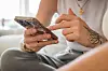 Person bedient ein Smartphone auf dem Sofa und nutzt technische Barrieren gegen belästigende Silent Calls.