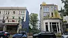 Historische und moderne Gebäude an einer belebten Straße mit vorbeifahrenden Autos und Baugerüst.