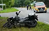 Beschädigtes Motorrad liegt im Gras, dahinter stehen Einsatzkräfte und ein Rettungswagen an der Straße.