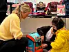 Erwachsene und Kinder betrachten in einem Fachgeschäft einen bunten Schulranzen.