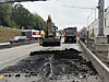 Bagger und Lastwagen bei Straßenarbeiten auf einer innerstädtischen Fahrbahn
