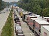 Dichter Lastwagenstau auf einer Autobahn neben einer weitgehend freien Fahrbahn