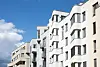 Moderne Mehrfamilienhäuser unter blauem Himmel; bei Immobilienerbe kann die Eigennutzung steuerlich entscheidend sein.