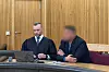 Angeklagter sitzt neben seinem Anwalt an einem Gerichtstisch im Gerichtssaal.